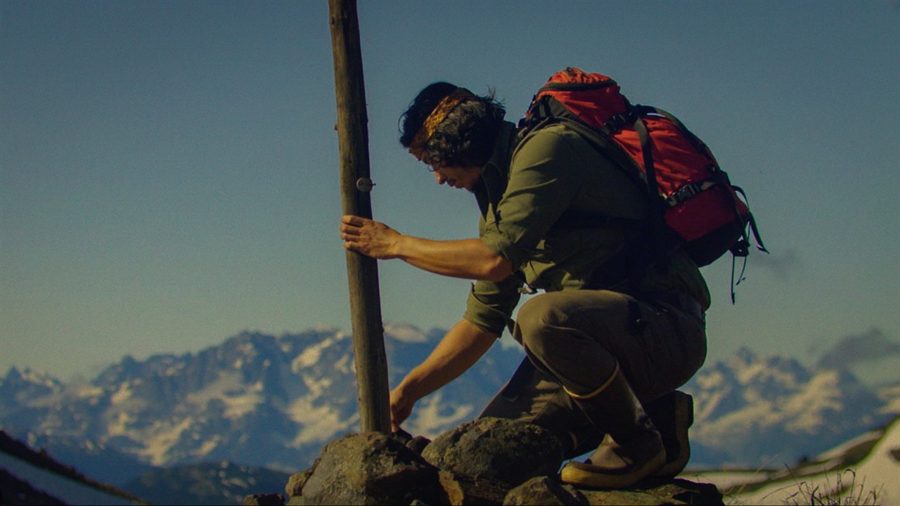 A crouching person securing a pole to rocks